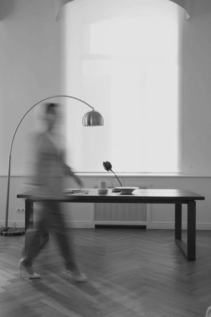 Interior minimalista com luminária de arco e mesa de madeira, em preto e branco