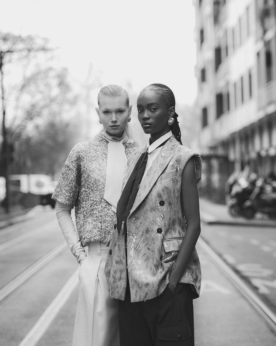 Duas modelos com styling sofisticado em rua de cidade europeia, em preto e branco
